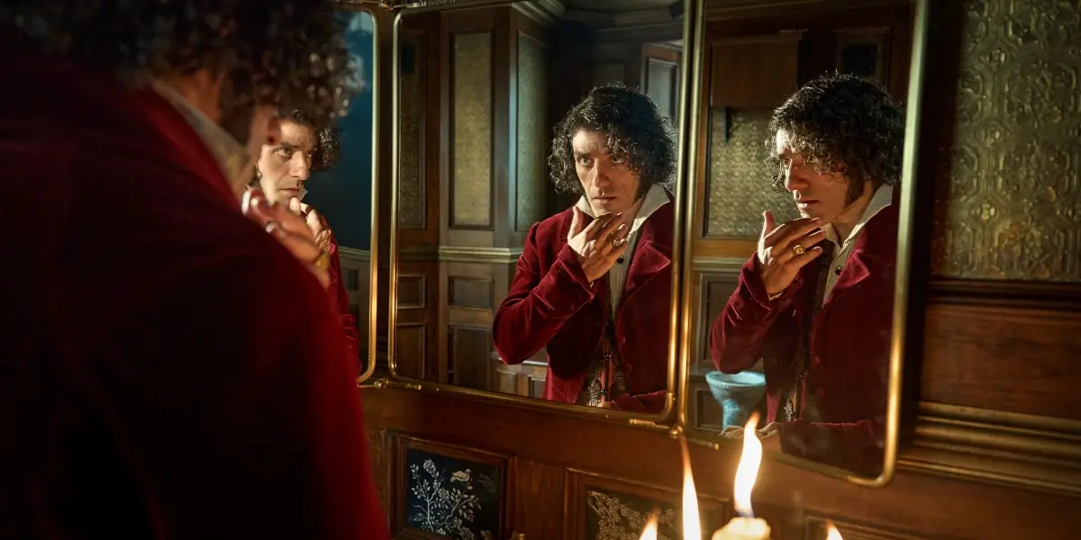 Oscar Isaac examines his face in a tri-panel mirror in Frankenstein.
