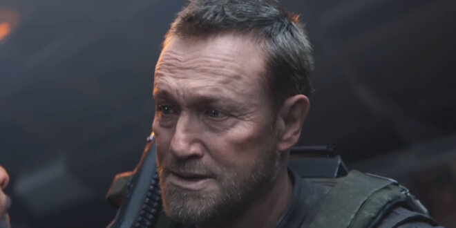 Michael Rooker stands in conversation in a cargo hold during Call of Duty: Black Ops 7 gameplay.