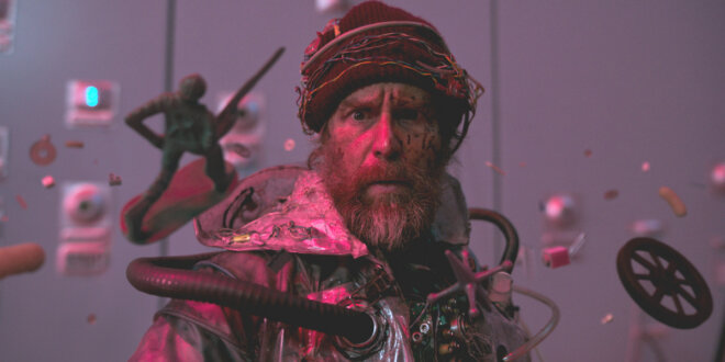 Sam Rockwell stands looking confused while dressed in trash in Good Luck, Have Fun, Don't Die.