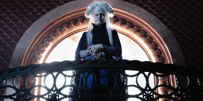 An older Caleb Landry Jones looks down from a balcony with curiosity in Dracula.