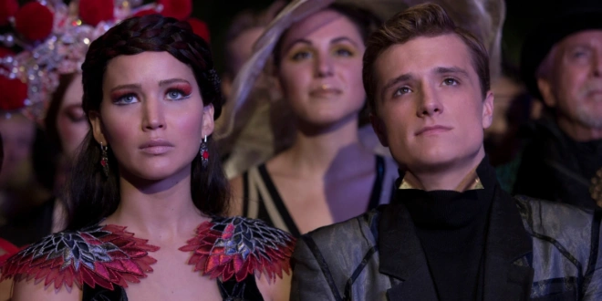 An unimpressed Jennifer Lawrence and Josh Hutcherson sit in an audience in The Hunger Games: Catching Fire.
