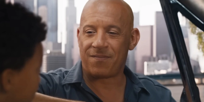 Vin Diesel smiles while leaning in through a car window in Fast X.