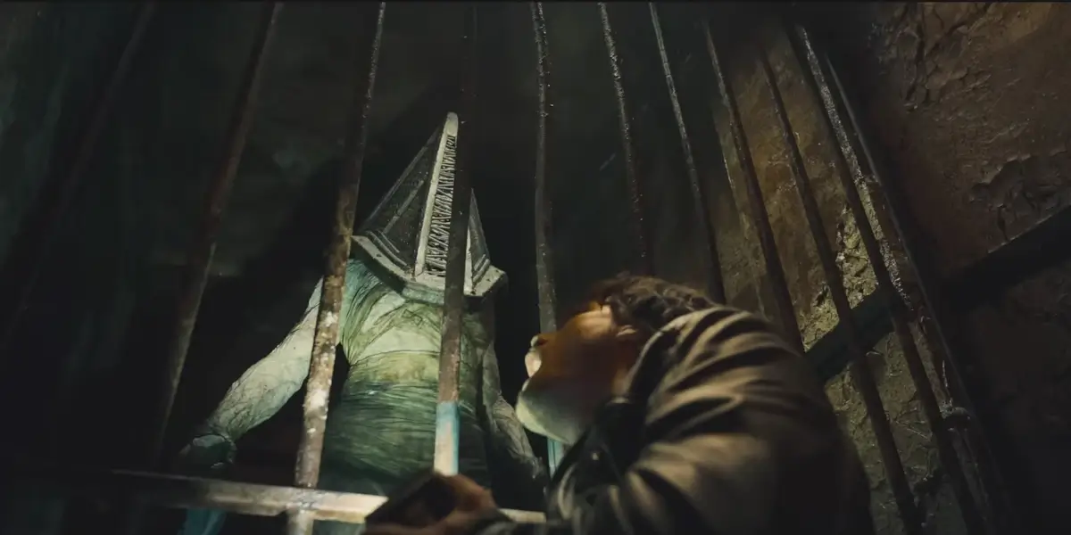 A Pyramid Head looms over Jeremy Irvine behind a cell door in Return to Silent Hill.