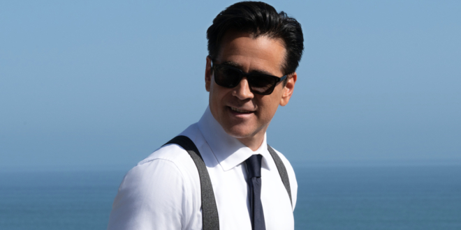 Colin Farrell stands in front of the ocean smiling in sunglasses, in Sugar Season 2.