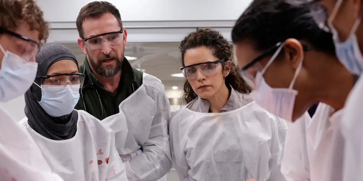 What We're Watching - Gerran Howell, Amielynn Abellera, Noah Wyle, Sepideh Moafi, Supriya Ganesh shown huddled together in scrubs in The Pitt Season 2.