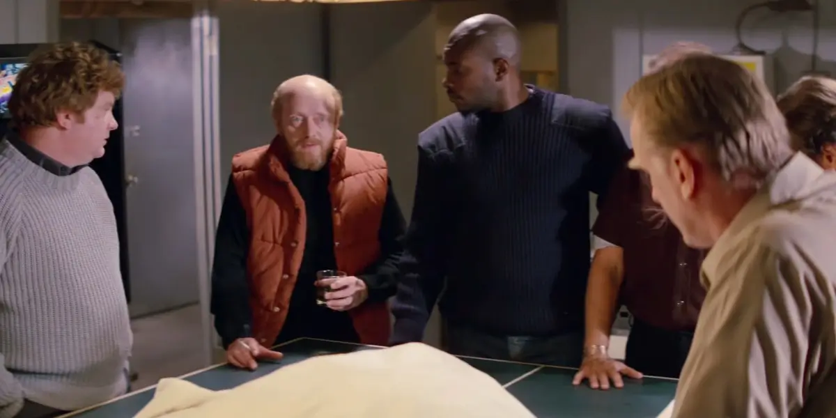 Members of the outpost crew stand around an examining table in The Thing.