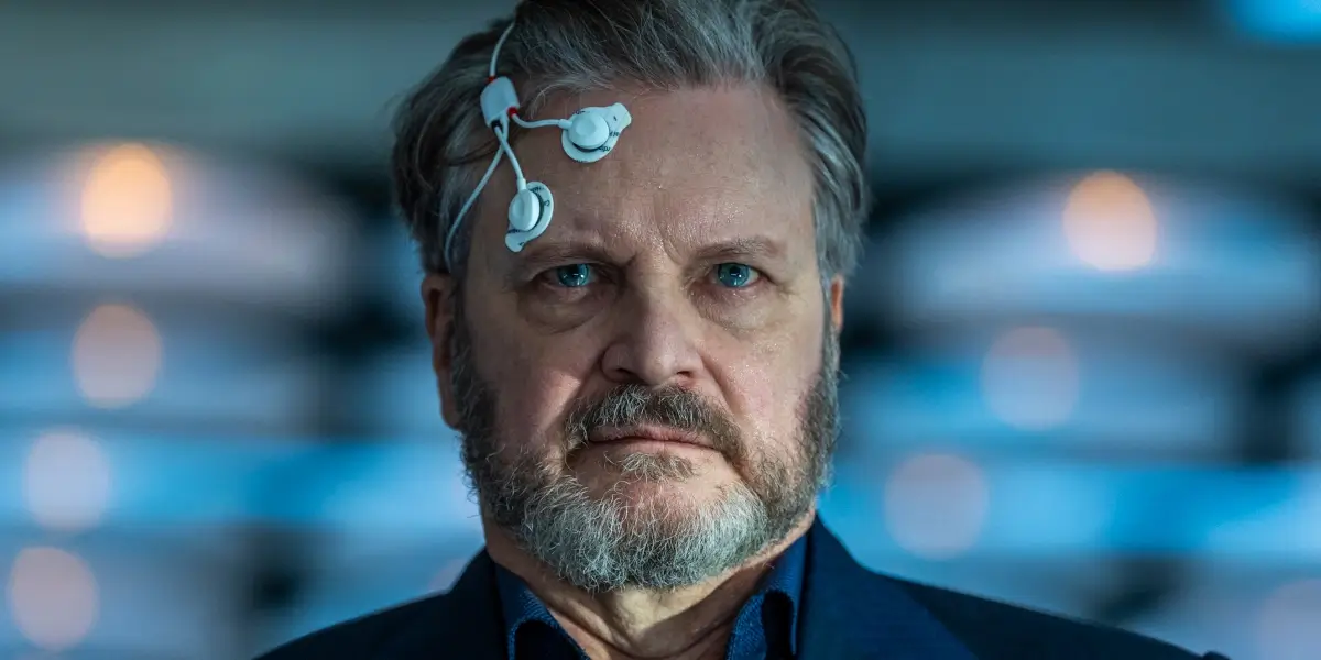 Colin Firth looks ahead with focus wearing sensors on his head in Disclosure Day.