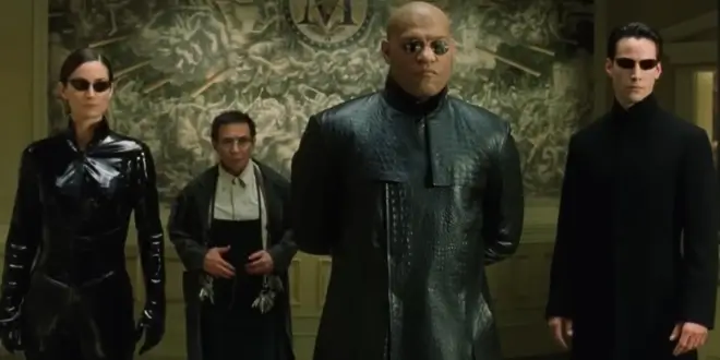 Carrie Anne Moss, Randall Duk Kim, Lawrence Fishburne, and Keanu Reeves stand grouped in the Merovingian's lair in The Matrix Reloaded.