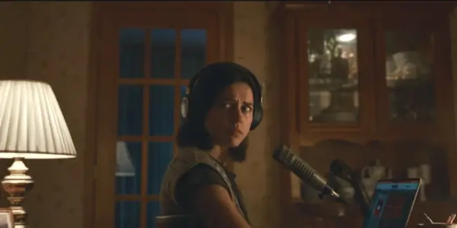 Nina Kiri looks behind her with worry while sitting at her desk in Undertone.