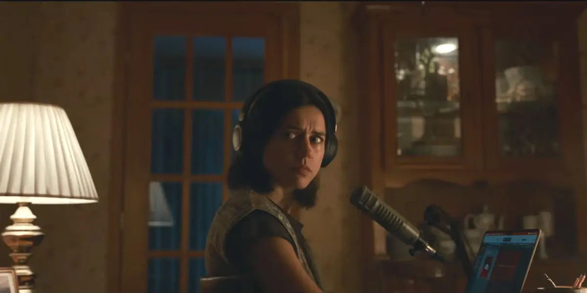 Nina Kiri looks behind her with worry while sitting at her desk in Undertone.