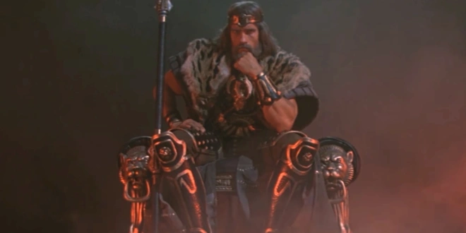 Arnold Schwarzenegger sits on a throne slumped in thought in Conan The Barbarian.