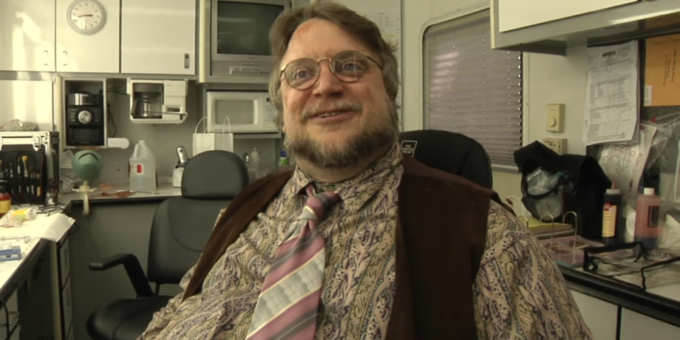 Guillermo del Toro sits smiling in a makeup chair in a behind the scenes featurette for It's Always Sunny in Philadelphia.
