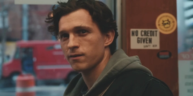 Tom Holland smiles wistfully in front of a doorway in Spider-Man: Brand New Day.