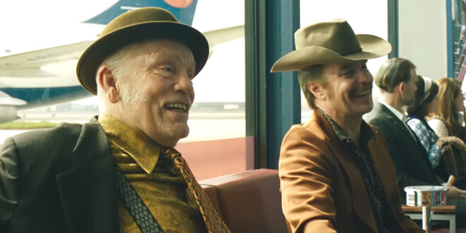 John Malkovich and Sam Rockwell sit with uneasy smiles in an airport in the Wild Horse Nine trailer.