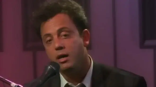 Billy Joel sings at the mic in the Piano Man music video.