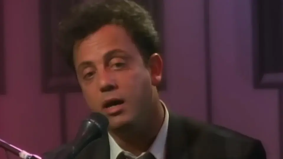 Billy Joel sings at the mic in the Piano Man music video.