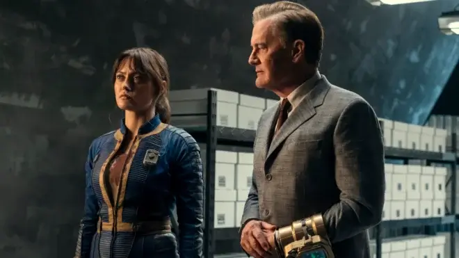 A wary Ella Purnell looks ahead as Kyle MacLachlan sternly watches in Fallout Season 2, Episode 7 - "The Handoff."