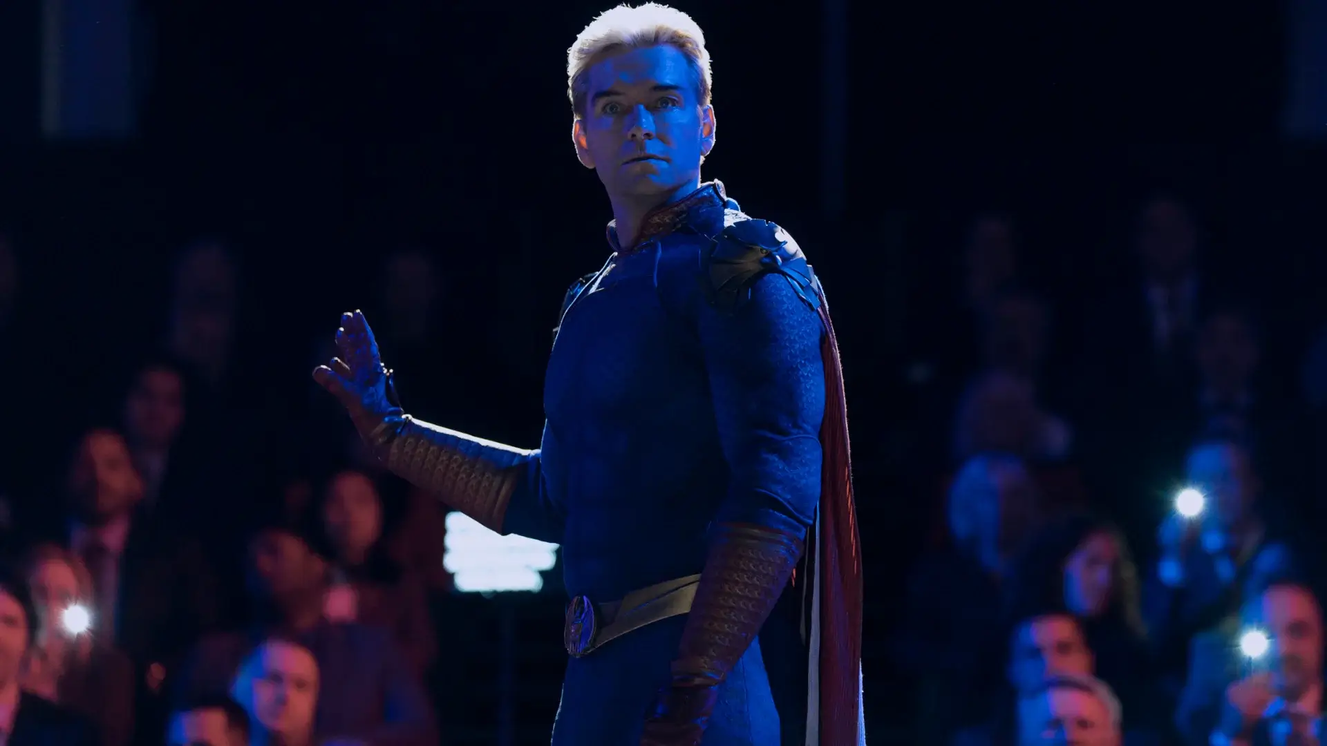 A half lit Antony Starr signals for silence from the crowd in The Boys S5.