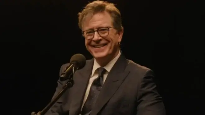 Stephen Colbert sits smiling in front of a microphone in The Late Show with Stephen Colbert's finale.
