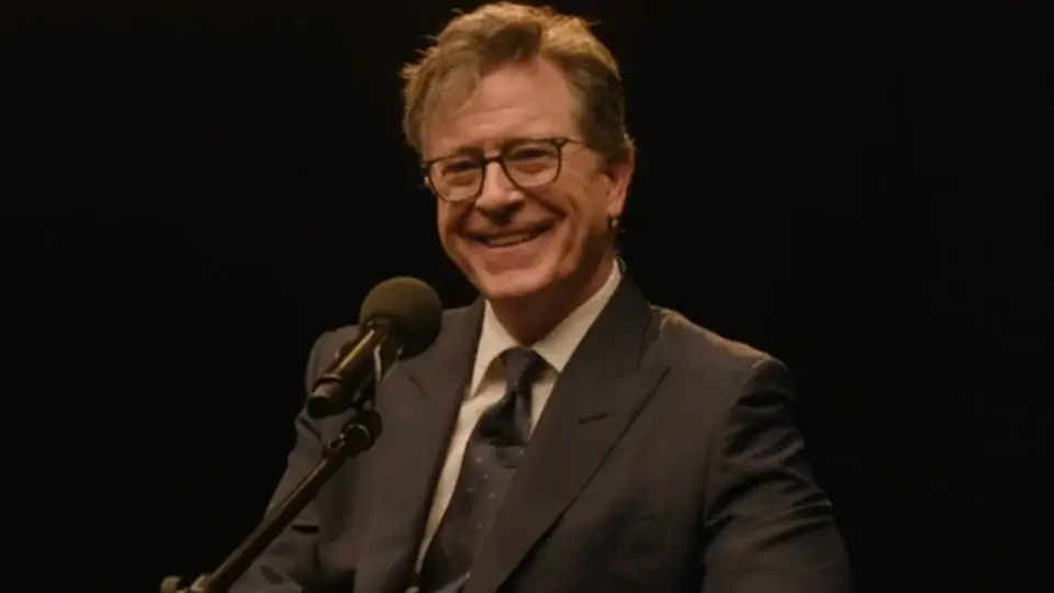 Stephen Colbert sits smiling in front of a microphone in The Late Show with Stephen Colbert's finale.