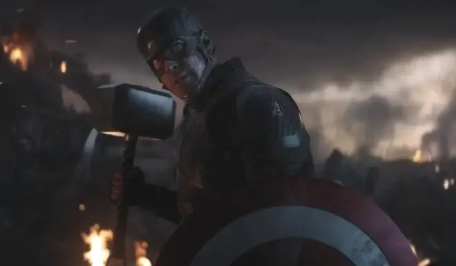 Chris Evans looks back defiantly while holding his Captain America's shield and Mjölnir in Avengers: Endgame.