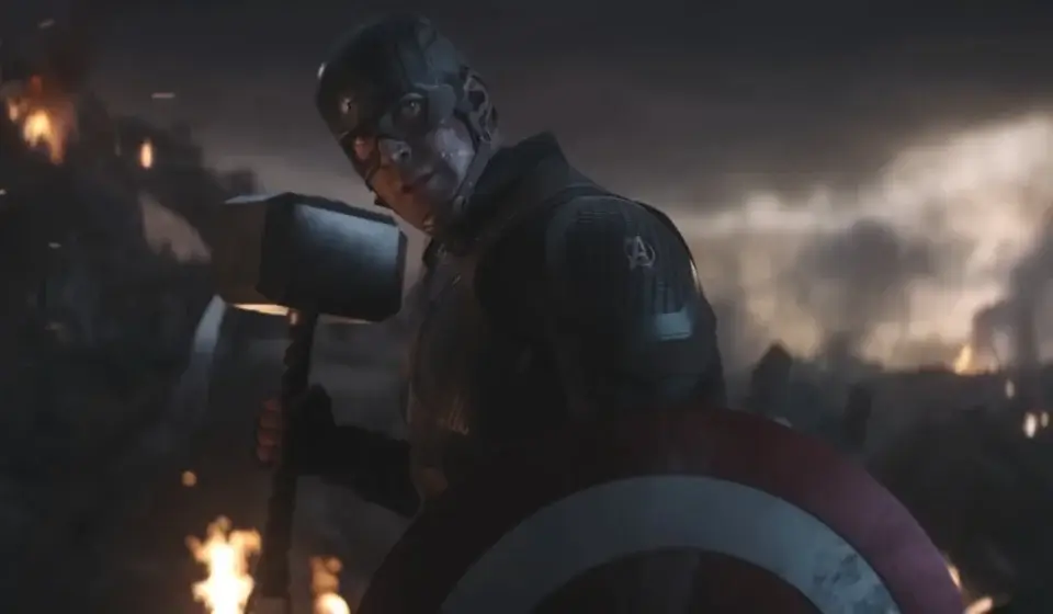 Chris Evans looks back defiantly while holding his Captain America's shield and Mjölnir in Avengers: Endgame.