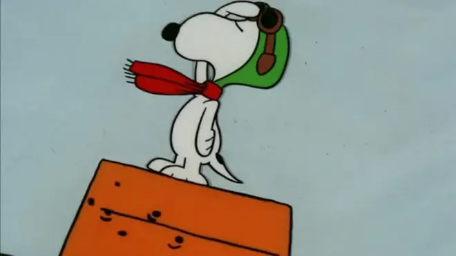 A saluting Snoopy stands on top of his doghouse, dressed as the World War I Flying Ace in It's The Great Pumpkin, Charlie Brown.
