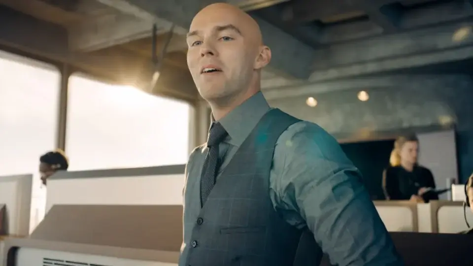 Nicholas Hoult stands with a cocky smile in the LuthorCorp control room in Superman.