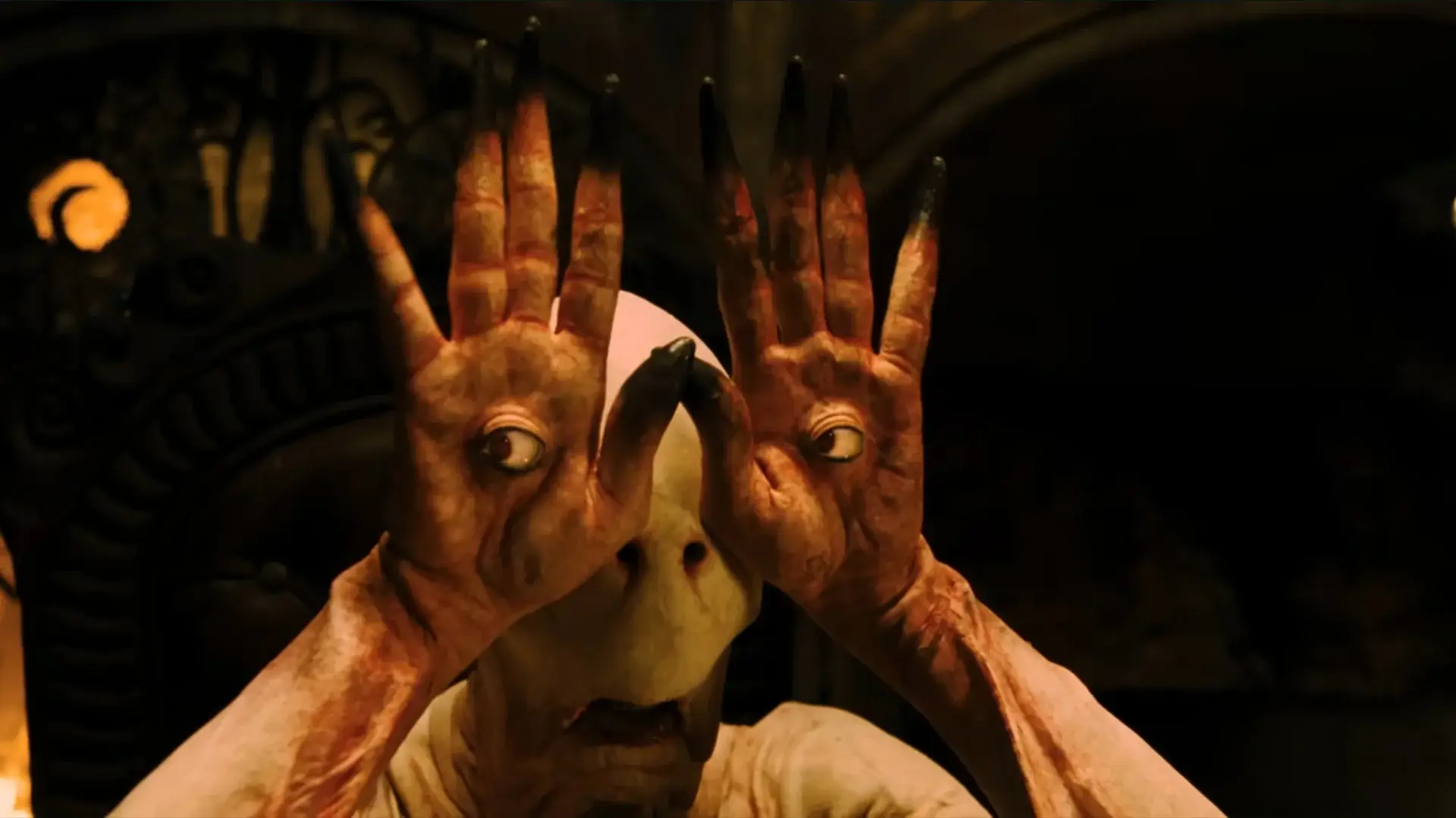 Doug Jones dressed as the Pale Man looks through his eyes embedded in his hands in Pan's Labyrinth.