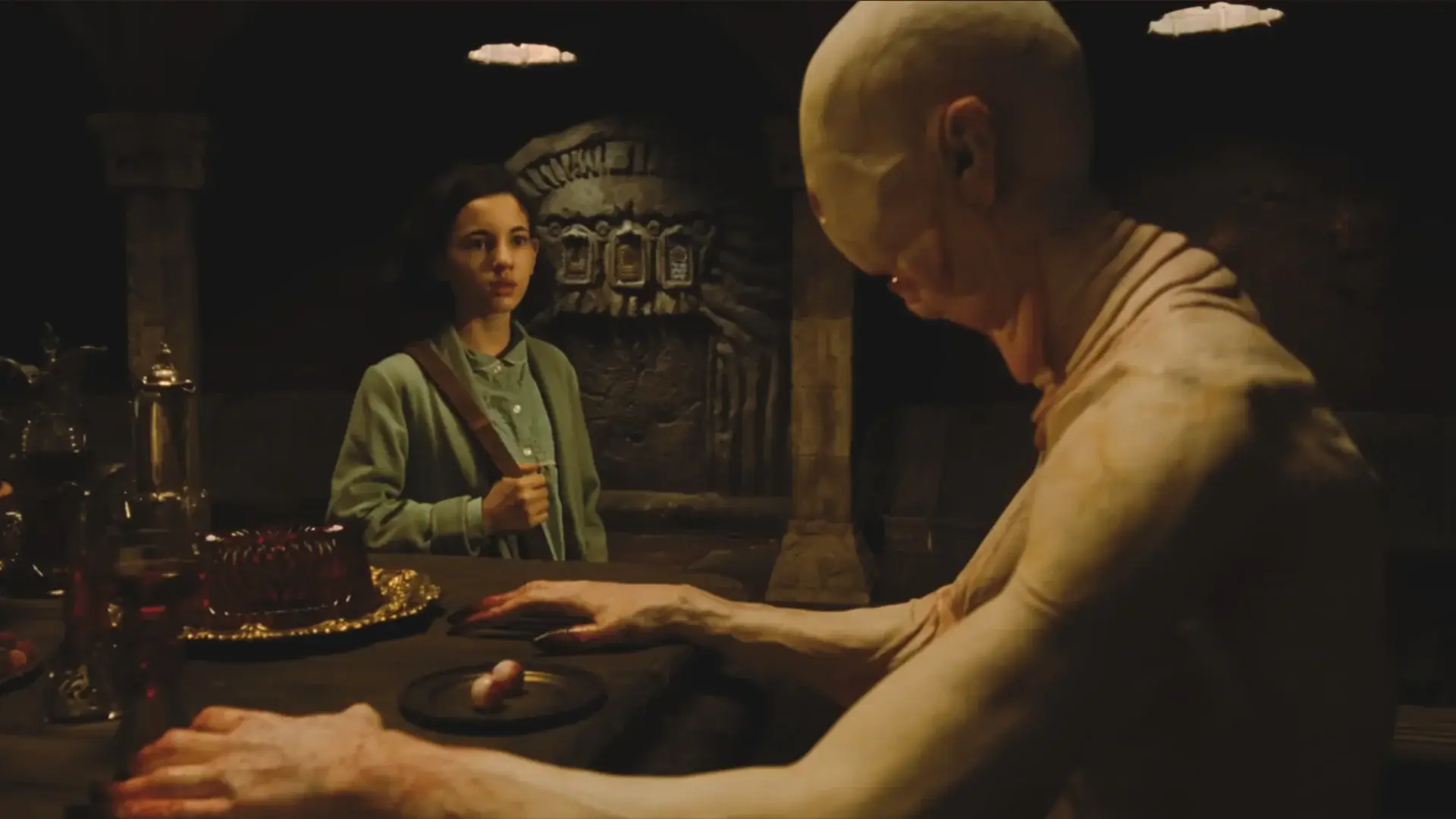 Ivana Baquero approaches Doug Jones sitting at a banquet table in full Pale Man costume and makeup in Pan's Labyrinth.