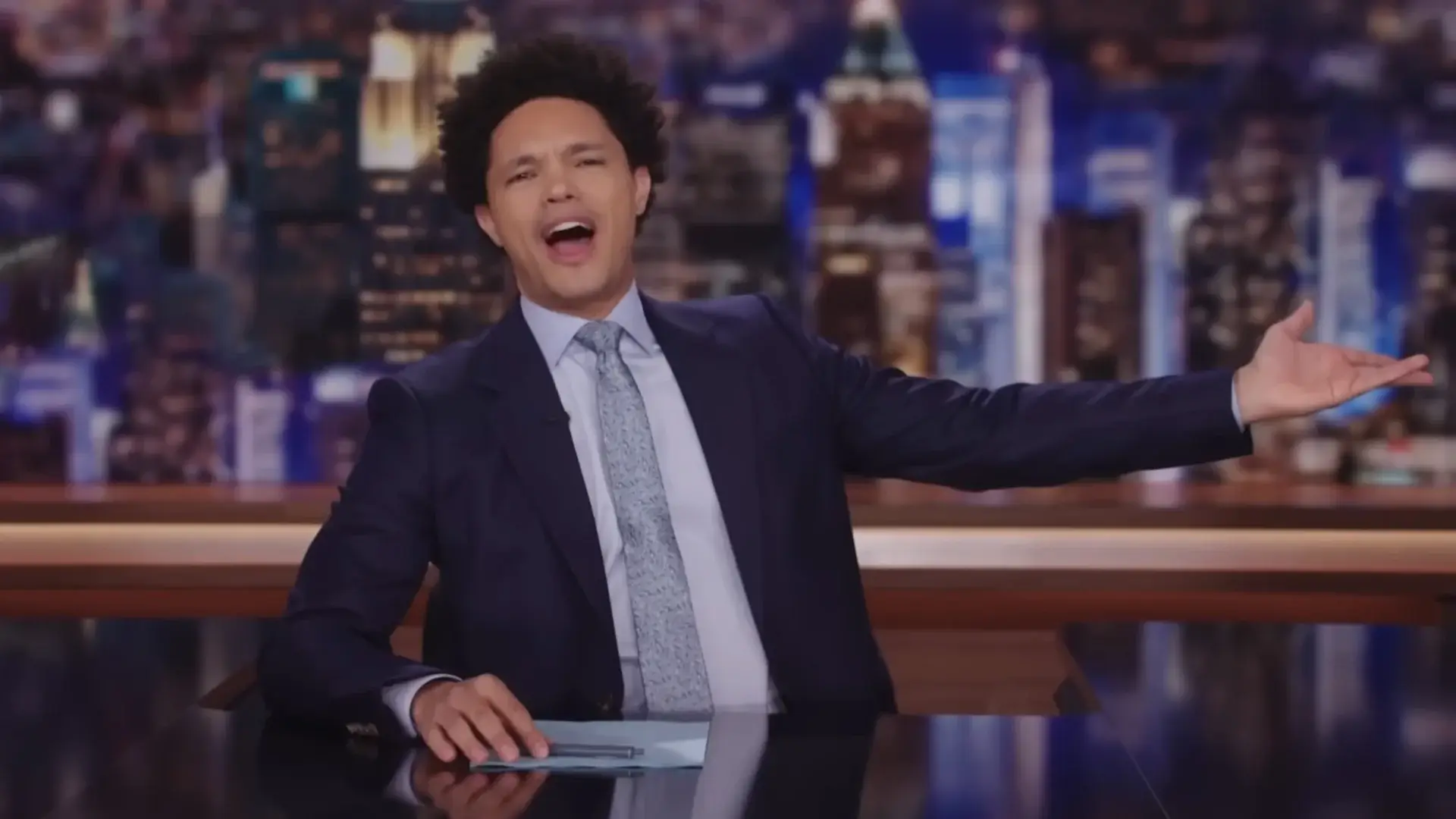 Trevor Noah gestures happily while sitting at the desk, in the last episode of The Daily Show with Trevor Noah.