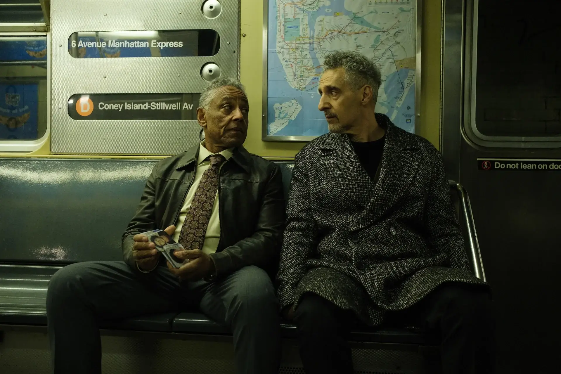 Two men looking at each other on a subway train.