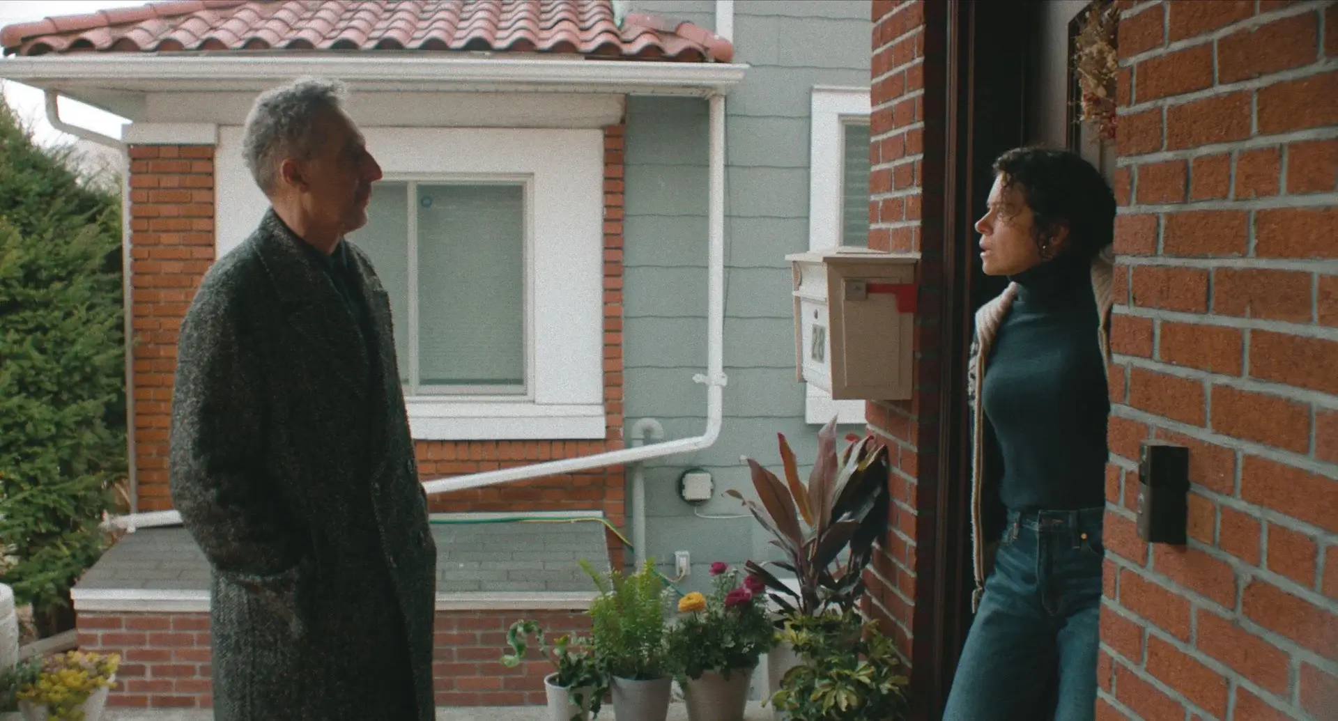 A man and woman talk on a porch.